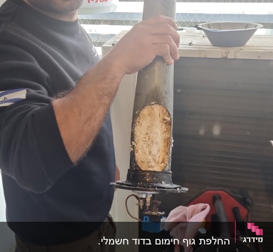 אדם מחזיק רכיב של דוד שמש עם אבנית
